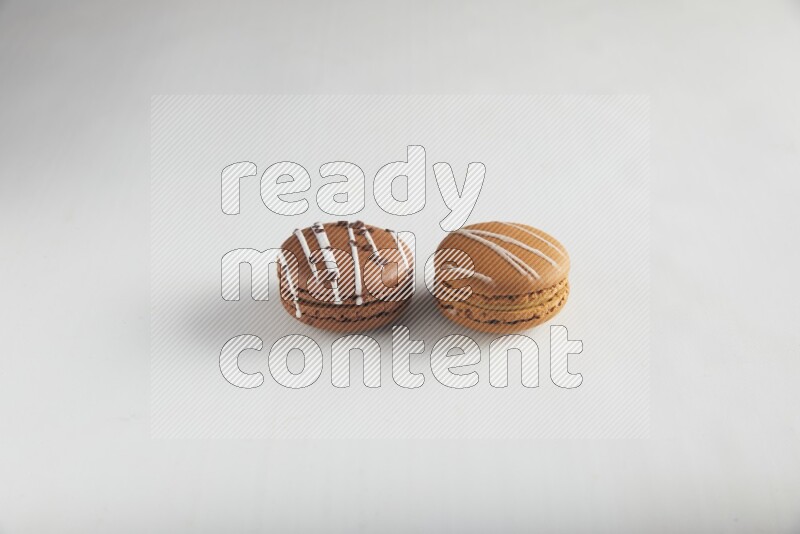 45º Shot of of two assorted Brown Irish Cream, and Brown white Chocolate Caramel macarons on white background
