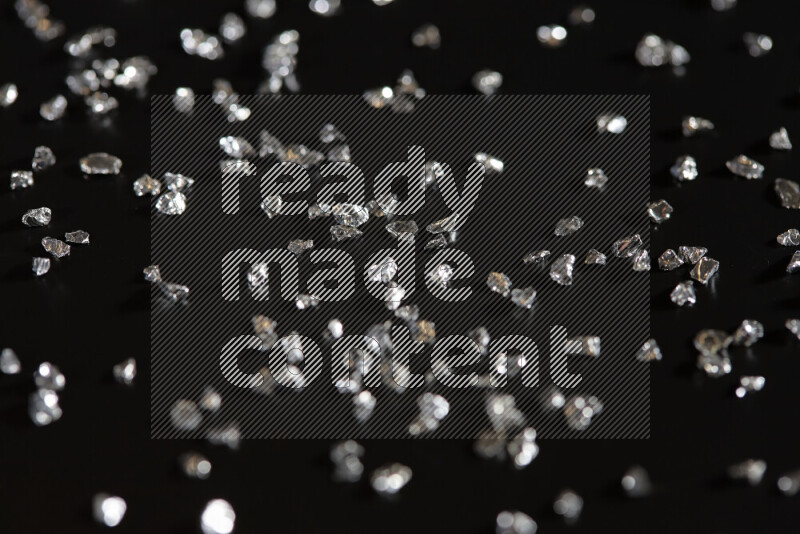 Silver shimmering fragments of glass scattered on a black background
