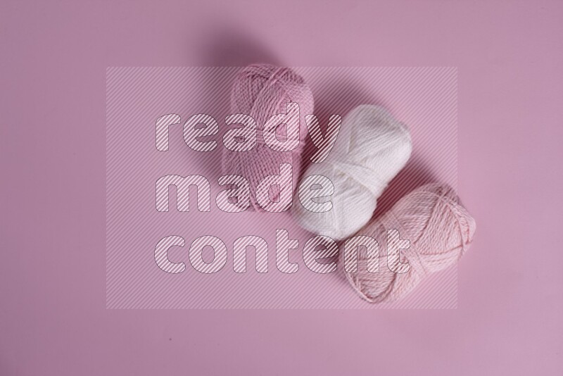 A white and pink collection of sewing and tailoring tools arranged on a pink background