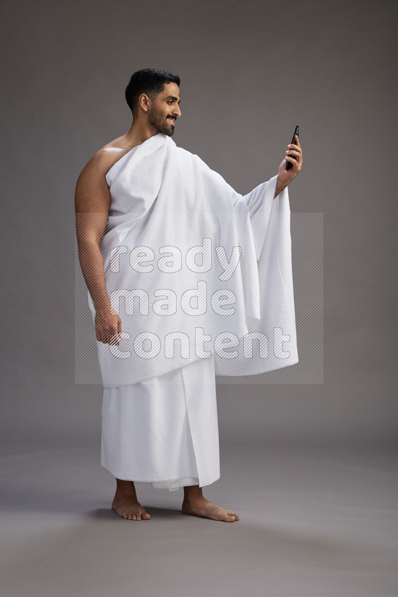 A man wearing Ehram Standing taking selfie on gray background