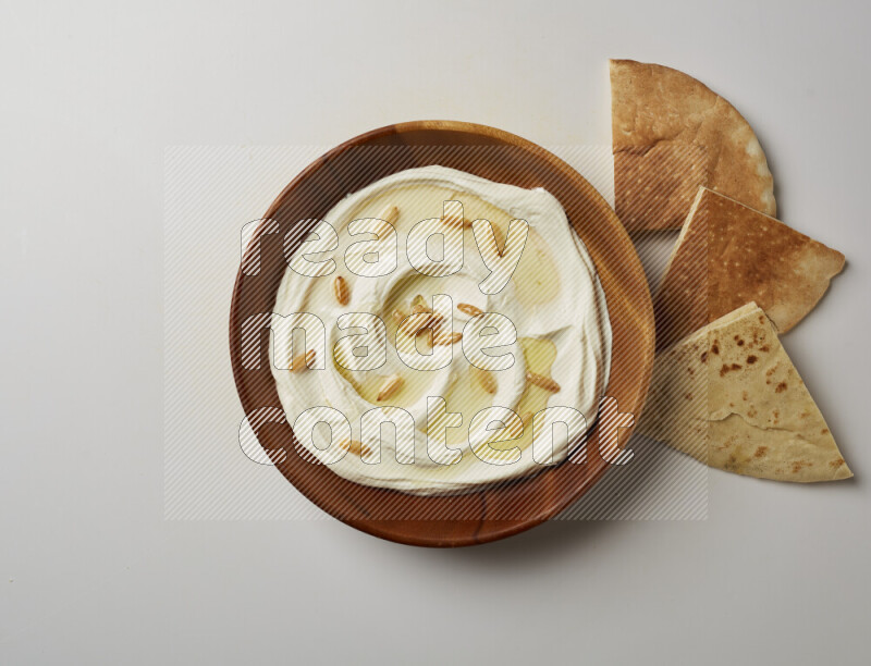 Lebnah garnished with pine nuts in a wooden plate on a white background