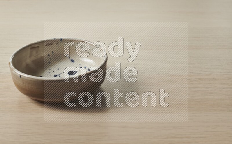 A multicolored pottery bowl on light wooden background
