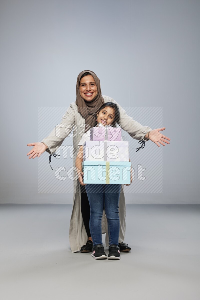 A girl giving a gift to her mother on gray background
