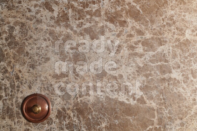 A small copper pot on beige marble background