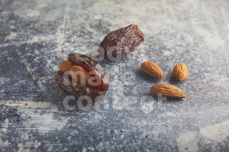 two almond stuffed madjoul dates on a rustic blue background