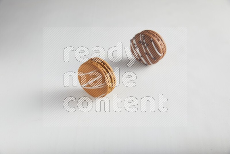 45º Shot of of two assorted Brown Irish Cream, and Brown white Chocolate Caramel macarons on white background