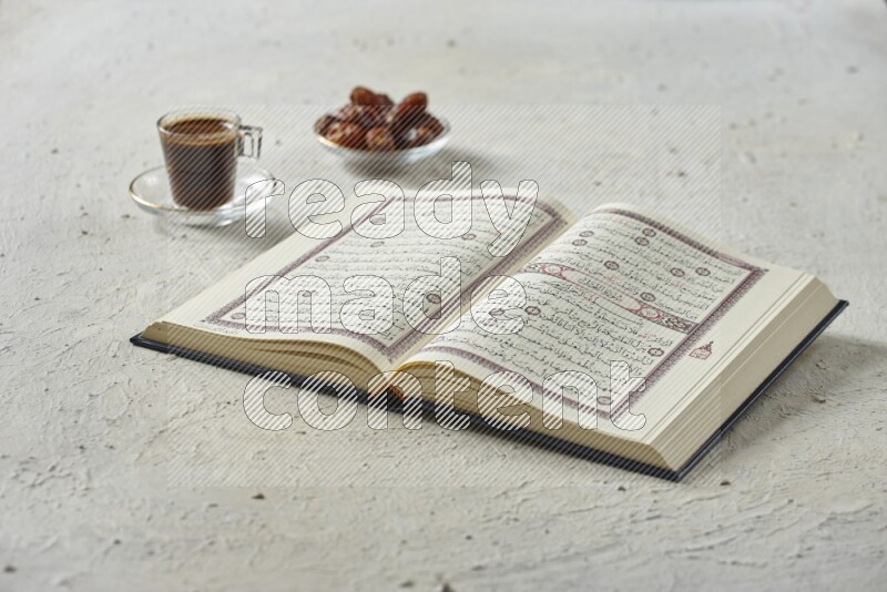 Quran with dates, prayer beads and different drinks all placed on textured white background