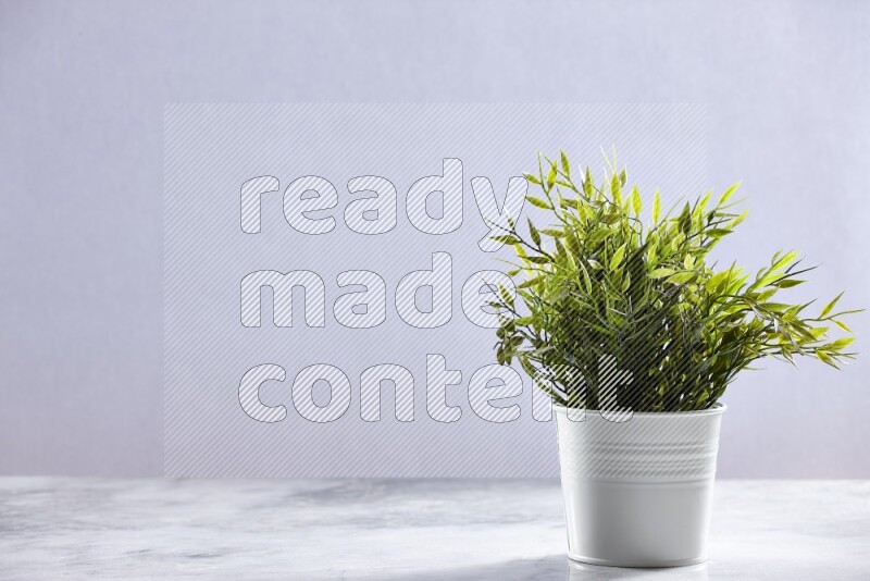 Green artificial plant in white pot on grey marble background