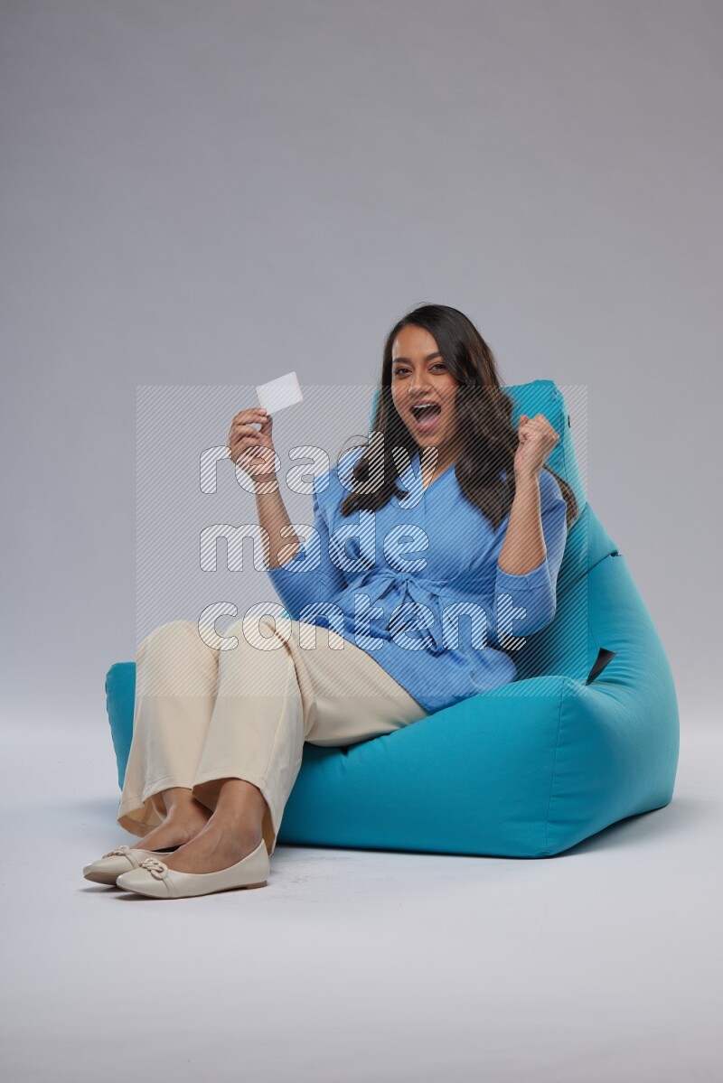 A woman sitting on a blue beanbag and holding ATM card