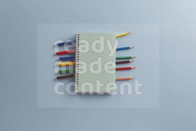 A blue notebook with different school supplies on blue background