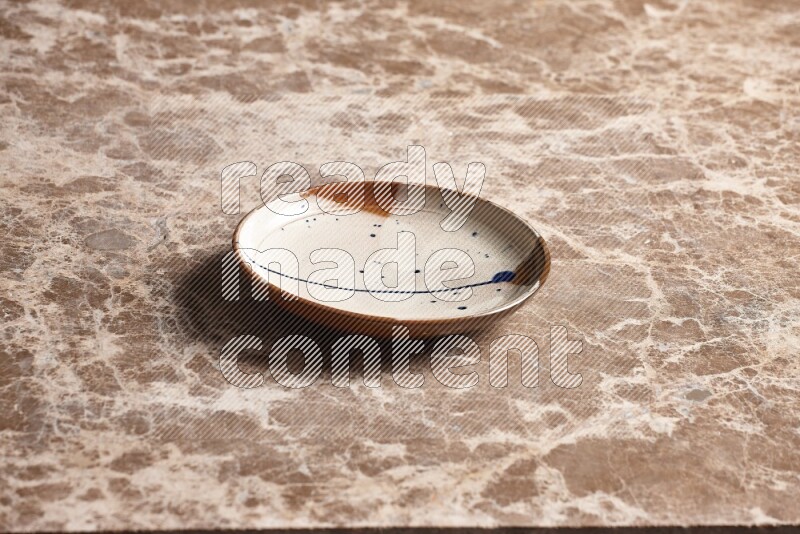 A multicolored pottery plate on beige marble background
