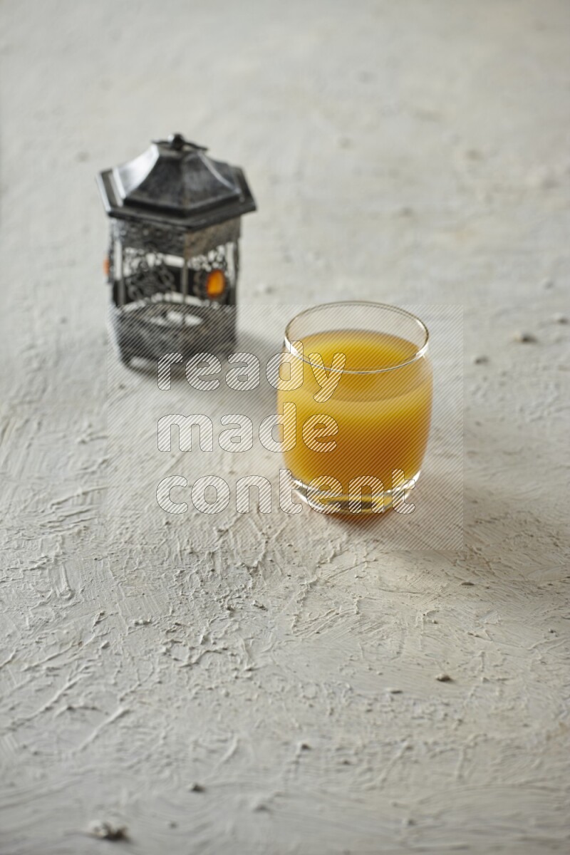 A silver lantern with different drinks, dates, nuts, prayer beads and quran on textured white background