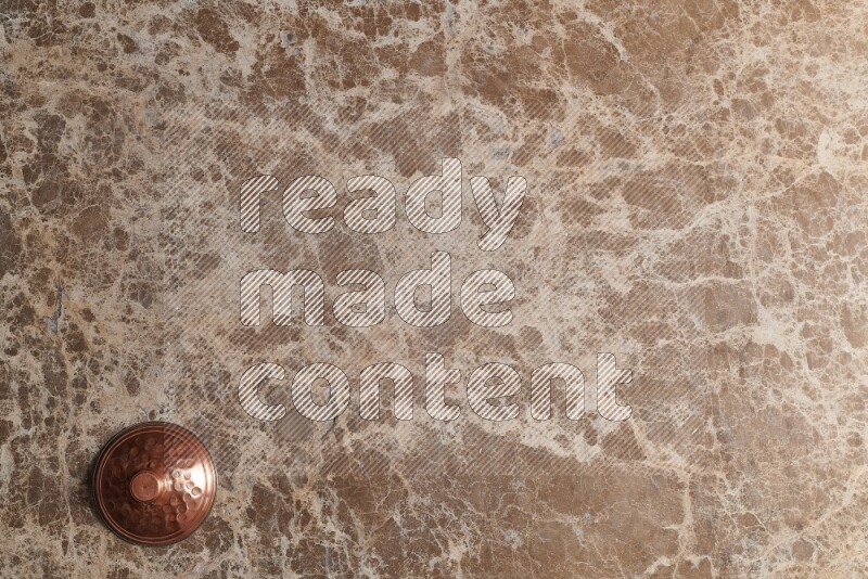 A small copper pot on beige marble background