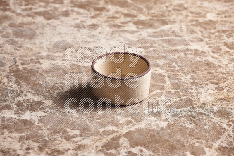 A beige pottery oven bowl on beige marble background