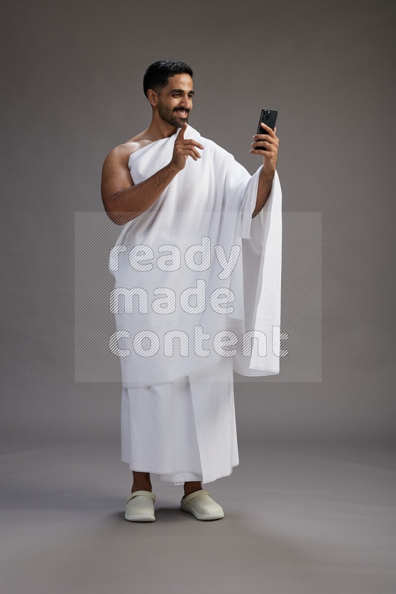 A man wearing Ehram Standing taking selfie on gray background