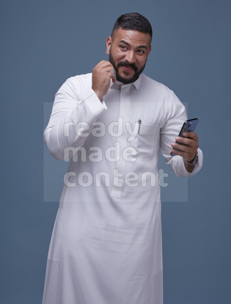 A man Texting on Blue Background wearing Saudi Thob