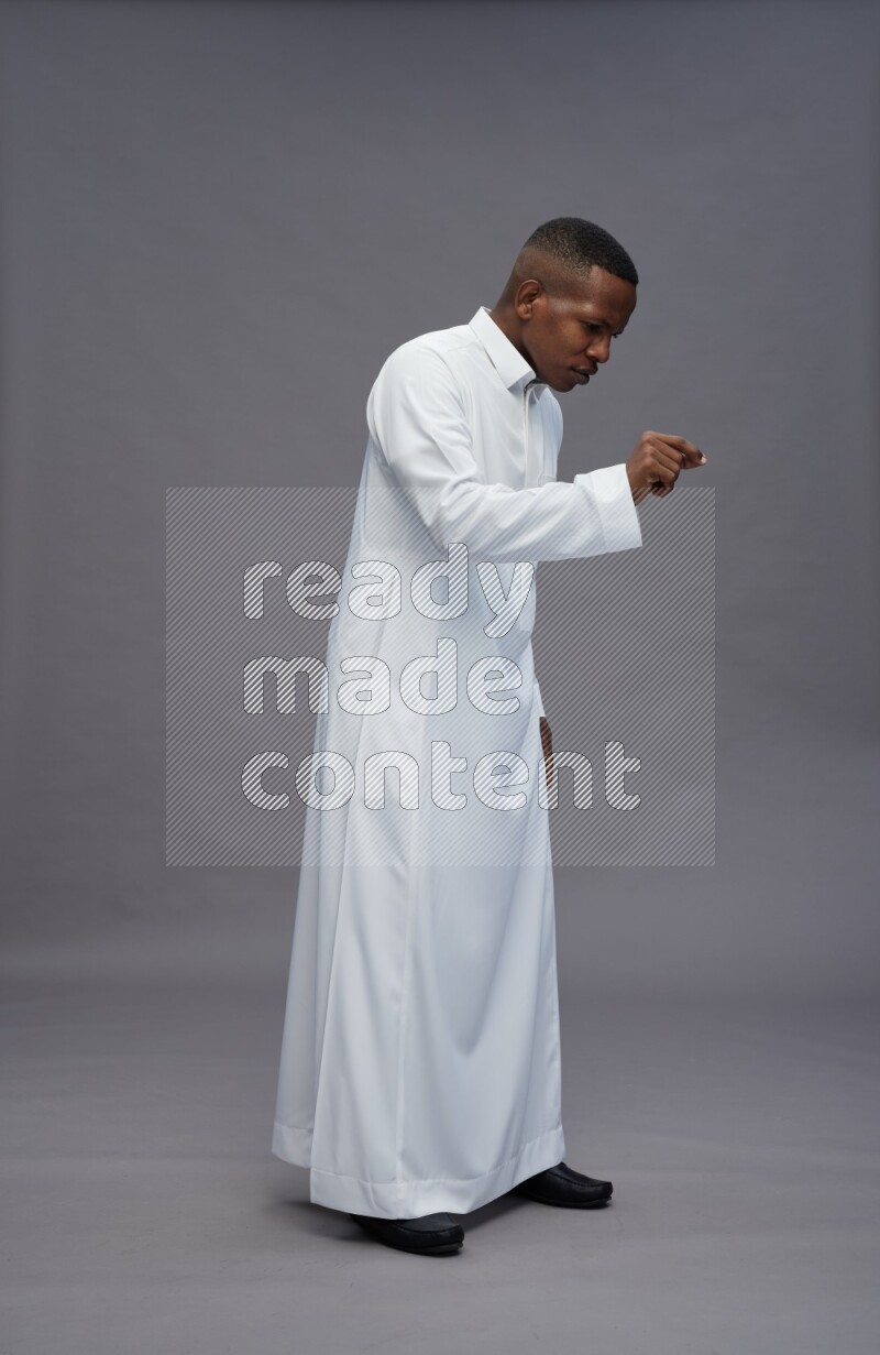 Saudi man wearing thob standing interacting with the camera on gray background