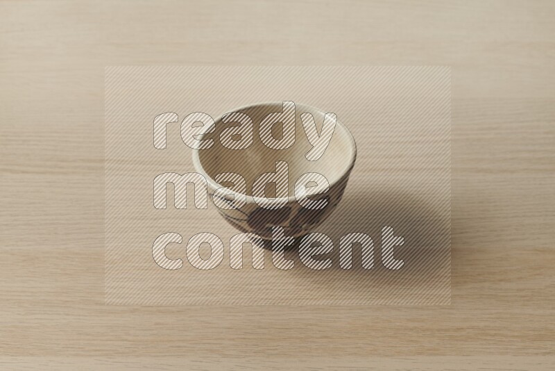A decorative pottery bowl on light wooden background