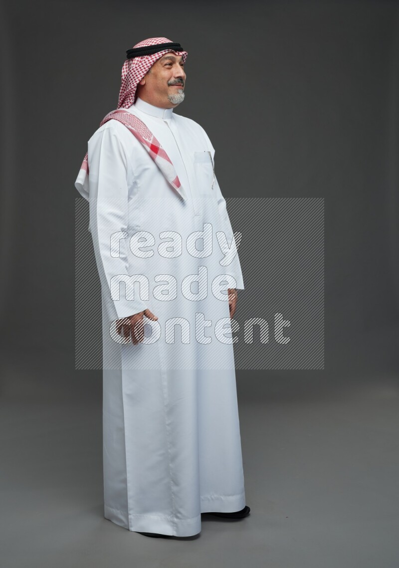Saudi man with shomag Standing Interacting with the camera on gray background