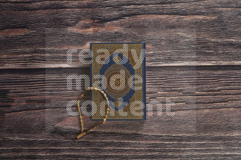 Quran with a prayer beads on wooden background