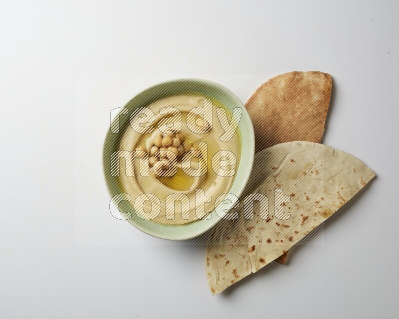 Hummus in a green plate garnished with roasted chickpeas  on a white background