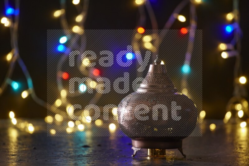 A traditional ramadan lantern surrounded by glowing fairy lights in a dark setup