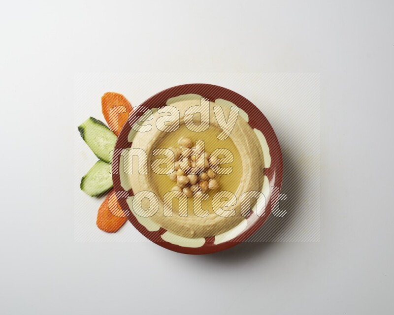 Hummus in a traditional plate garnished with roasted chickpeas  on a white background