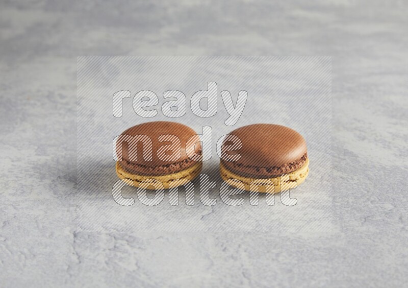 45º Shot of two Yellow and Brown Chai Latte macarons r on white  marble background