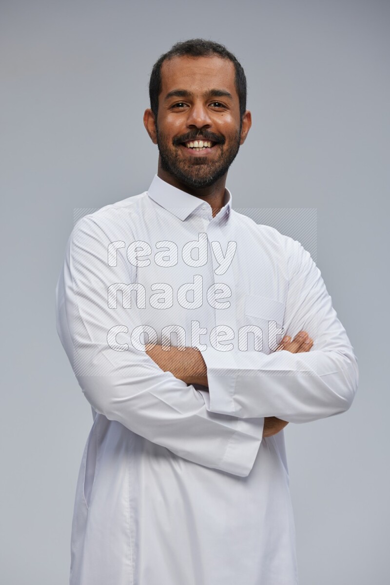 Saudi man wearing Thob standing with crossed arms on Gray background