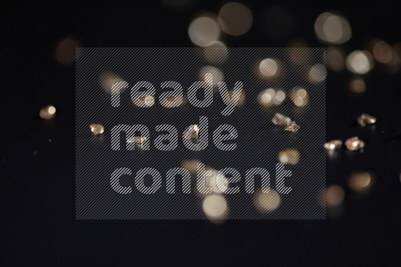 Gold shimmering fragments of glass scattered on a black background