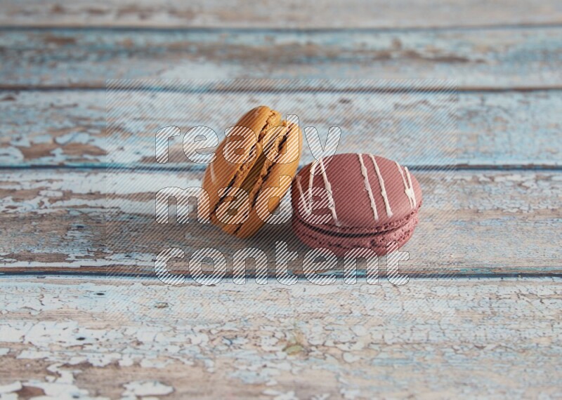 45º Shot of of two assorted Brown Irish Cream, and Red Poppy Flower macarons  on light blue background