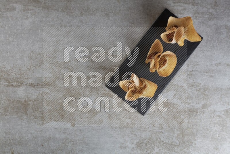 wonton cups with soy sauce ramkin on rectangle slate on grey textured counter top