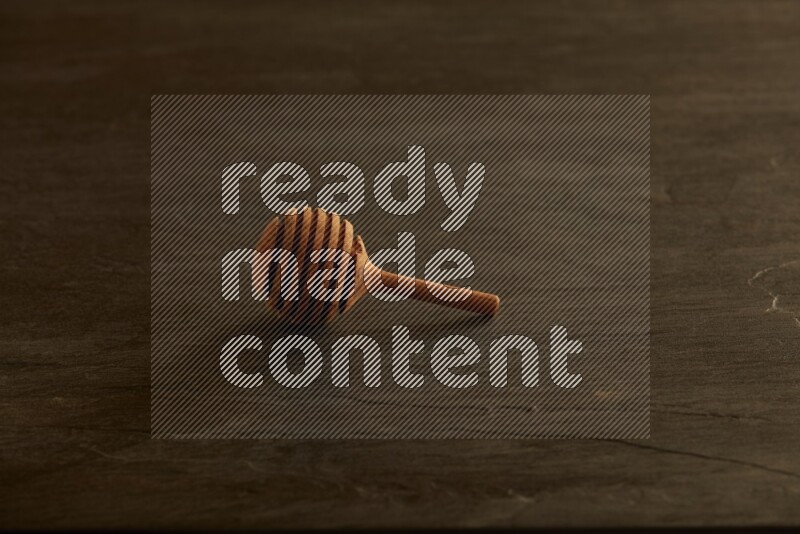 Wooden honey dipper on black slate background