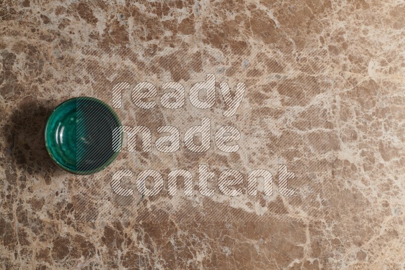 A dark green pottery bowl on beige marble background
