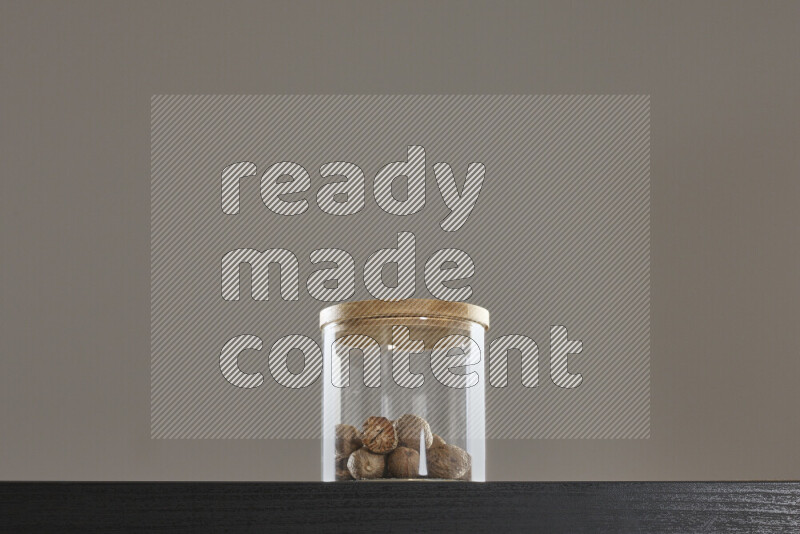 Nutmeg in a glass jar on black background