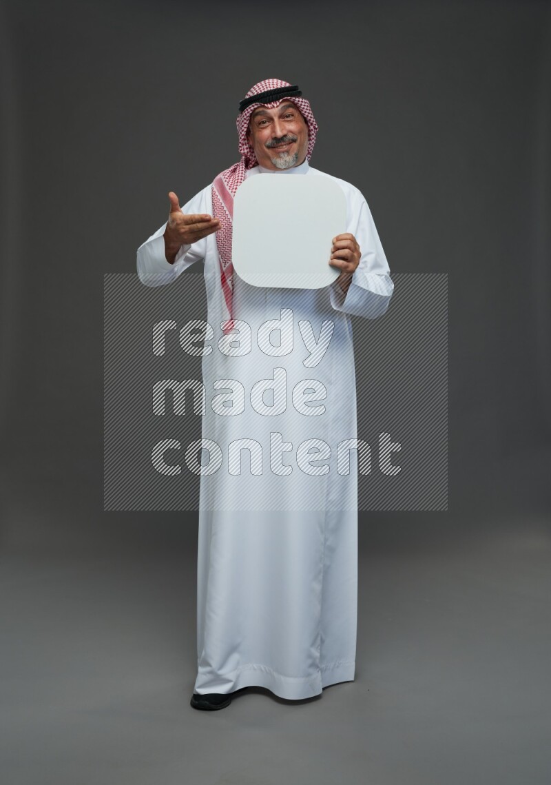 Saudi man with shomag Standing holding social media sing on gray background