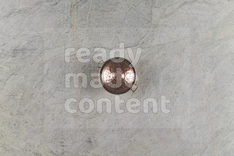 A small copper pot on grey marble background