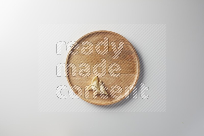 Two Sambosas on a wooden round plate on a white background