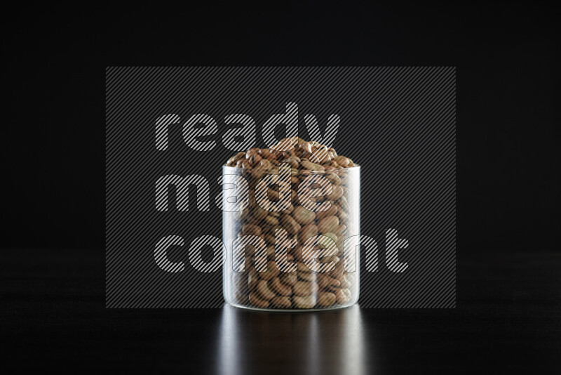 Fava beans in a glass jar on black background