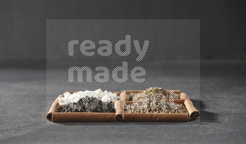 4 squares of cinnamon sticks full of black pepper, cumin, white pepper and white salt on black flooring