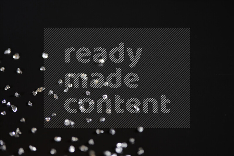 Silver shimmering fragments of glass scattered on a black background