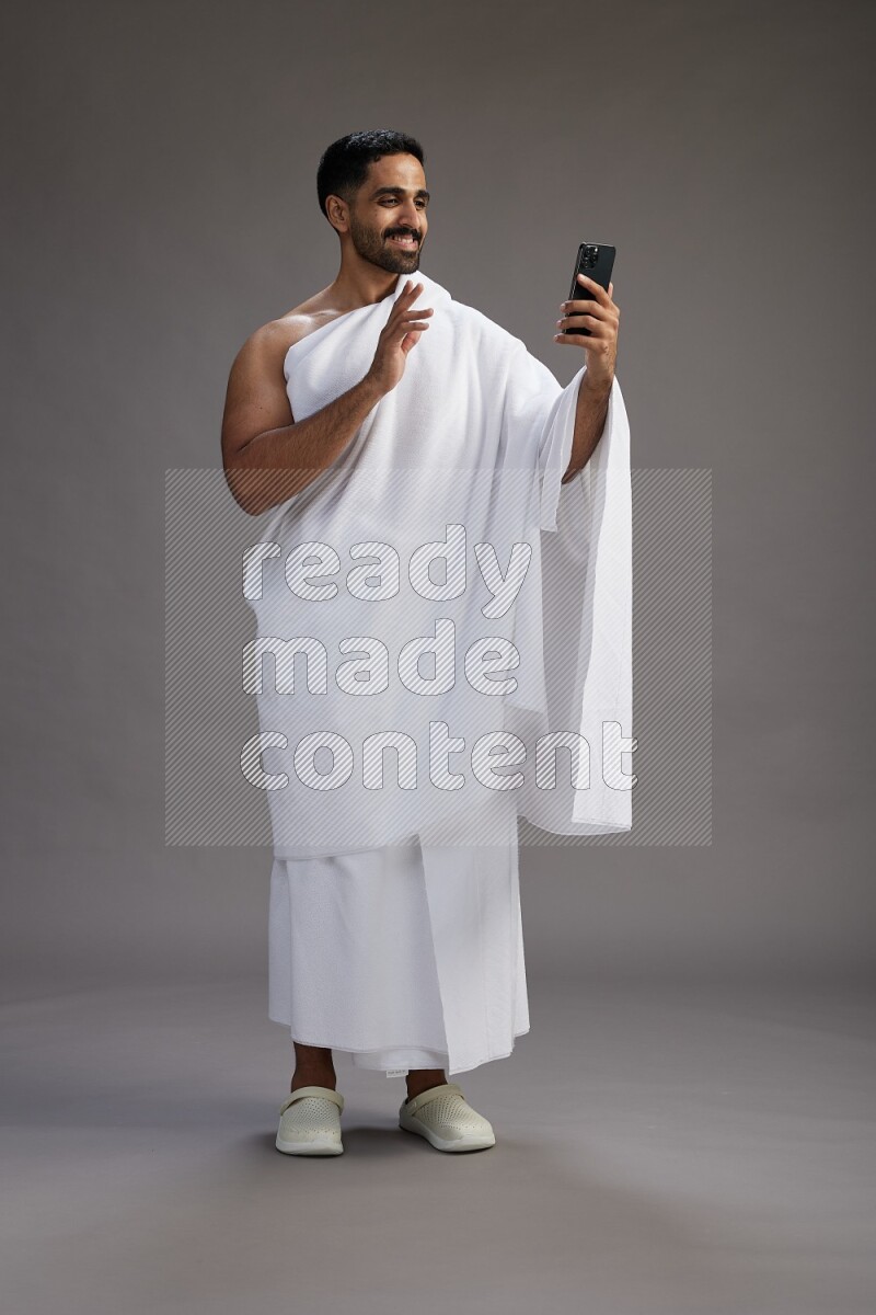 A man wearing Ehram Standing taking selfie on gray background