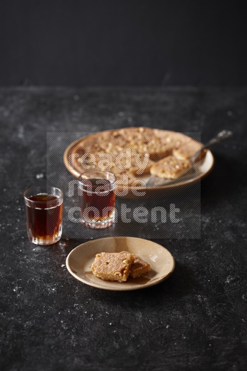 Basbousa with tea in a dark setup