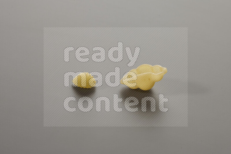 Shells pasta with other types of pasta on grey background