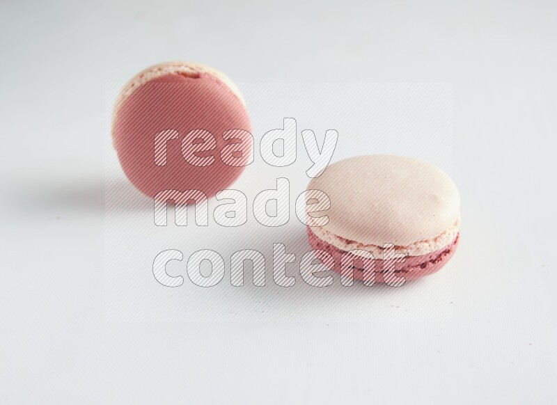 45º Shot of two Pink Litchi Raspberry macarons on white background