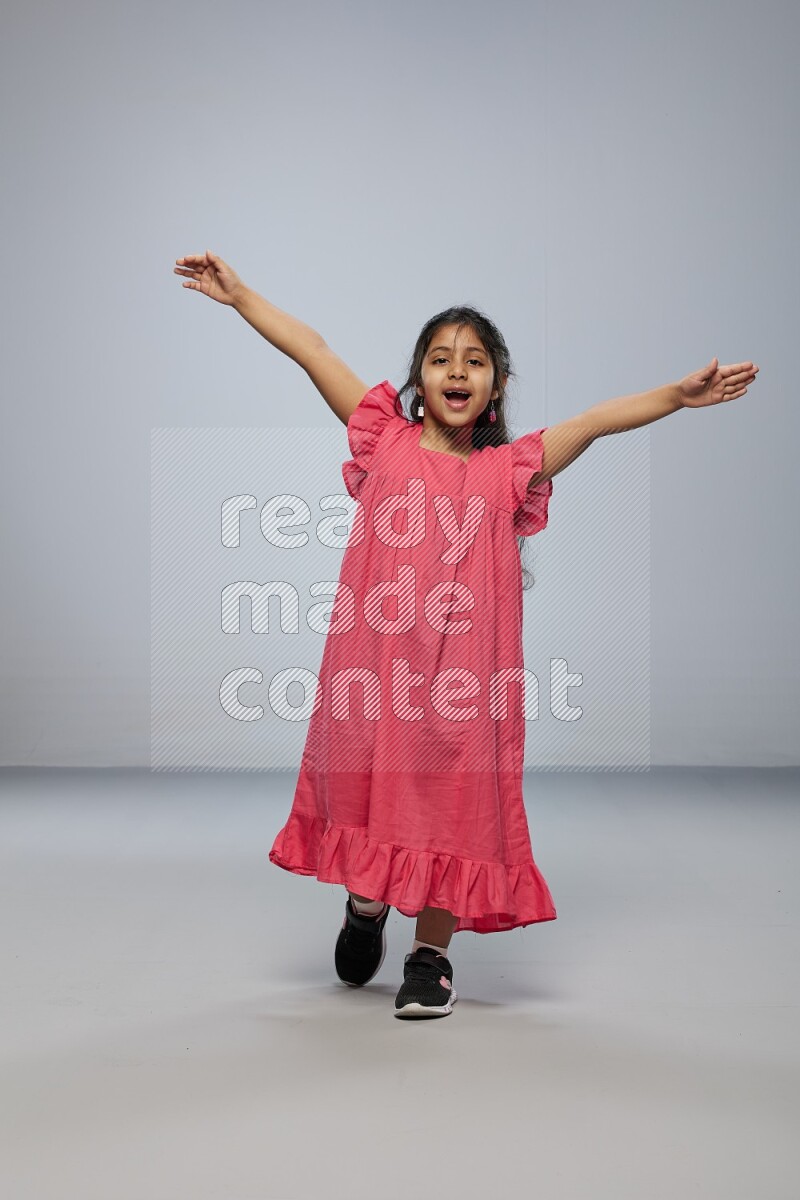 A girl standing interacting with the camera on gray background