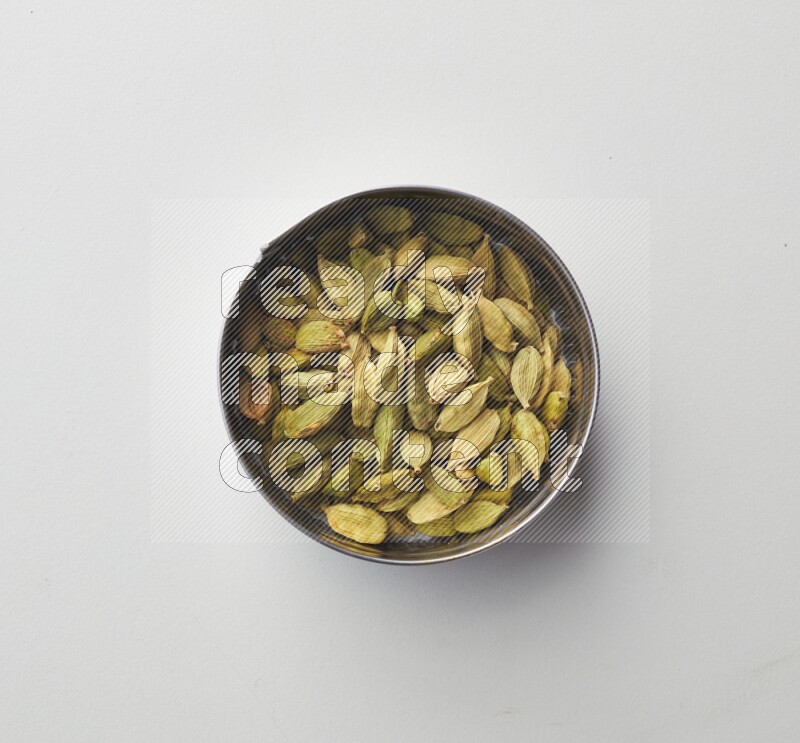 Top-view shot of Cardamon in a container on white background