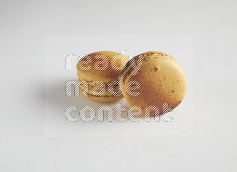 45º Shot of two Yellow Crème Brulée macarons on white background