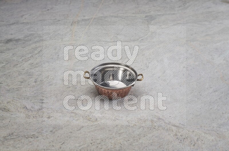 A small copper pot on grey marble background