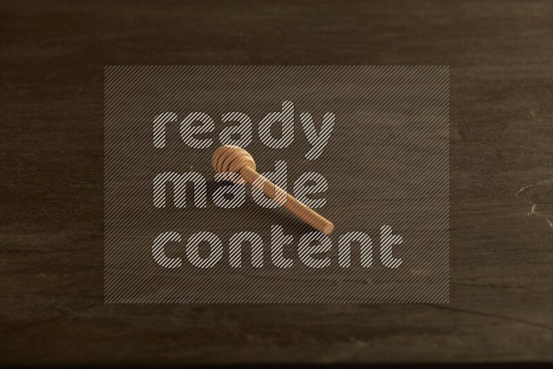 Wooden honey dipper on black slate background